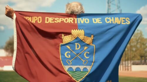 Bandeira do GD Chaves no relvado do estádio Municipal, segurada por um adepto