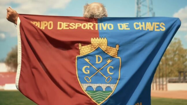 Bandeira do GD Chaves no relvado do estádio Municipal, segurada por um adepto